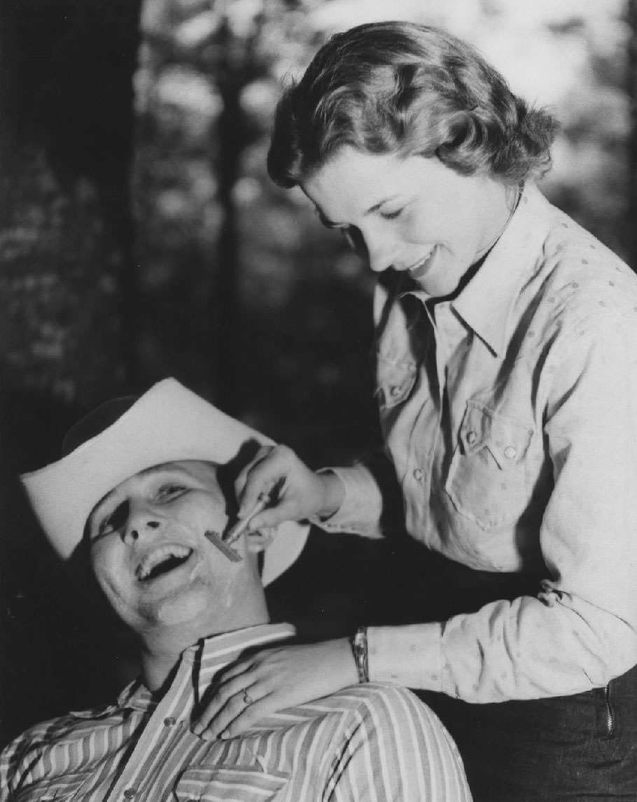 Student shaves man in cowboy hat, 1950s