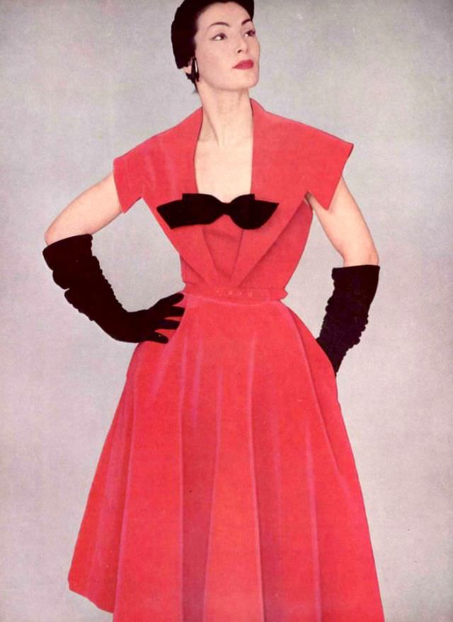 Lucky in pink geranium velvet cocktail dress adorned with black ribbon bow, by Jacques Fath, 1951