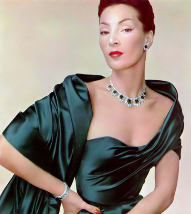 Lucky is wearing emerald green satin evening gown by Jacques Fath to compliment magnificent emerald and diamond parure by Cartier, 1951
