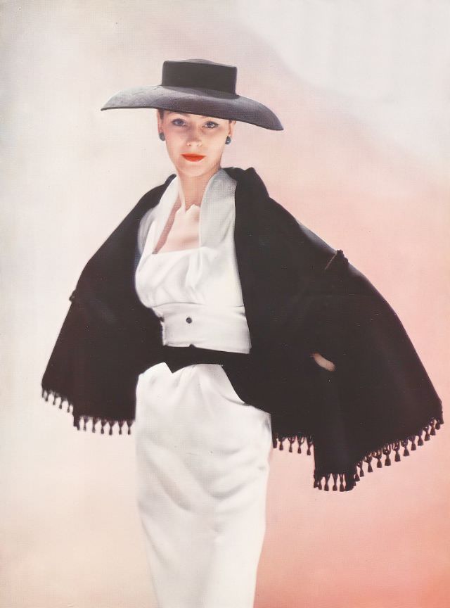 Anne Gunning is wearing a black grosgrain shawl in two layers with slits for the hands over a square-necked white grosgrain dress by Susan Small after Fath, 1952