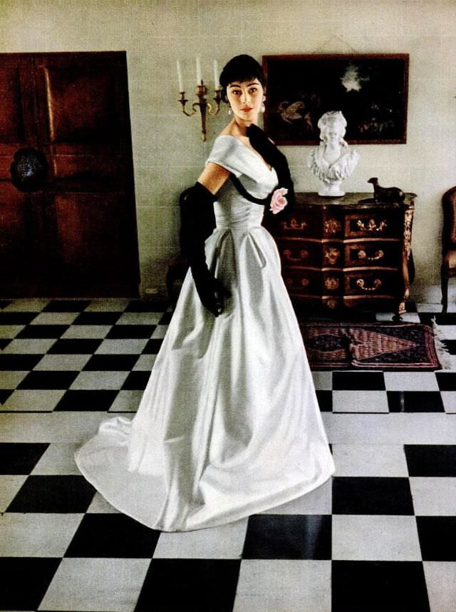 Anne Gunning in white satin gown with velvet ribbon outlining the bosom by Jacques Fath, photographed in the foyer at Fath's chateau at Corbeville by Mark Shaw, 1953