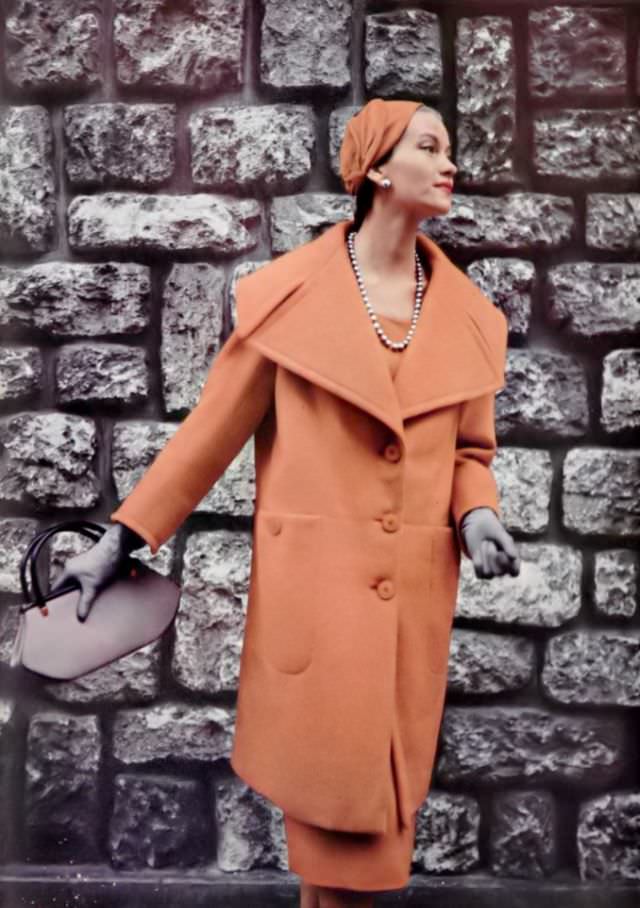 Anne Campion in orange wool coat in the new 3/4 length with deep indented collar and large pockets by Jacques Fath, 1954