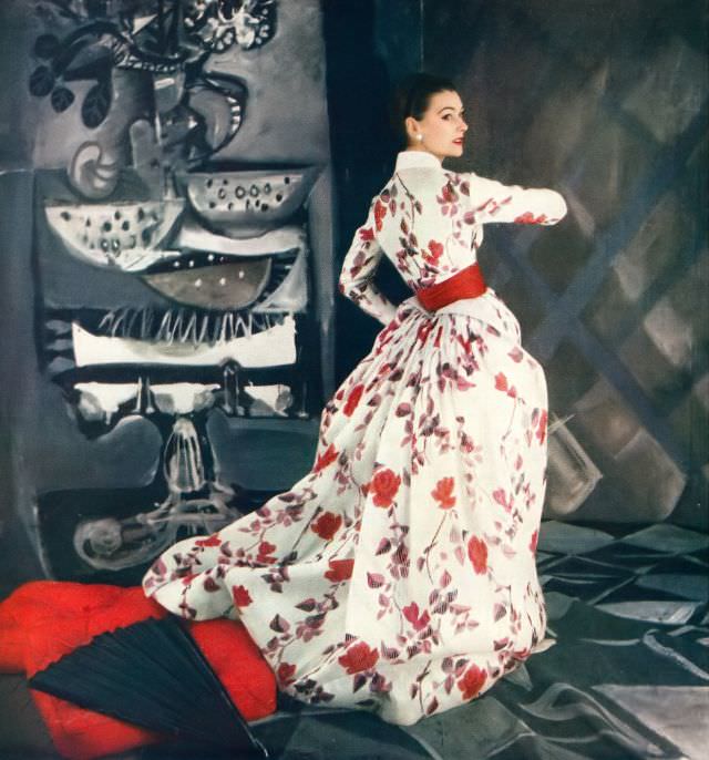 Anne Gunning in beautiful satin-striped silk organdy gown in floral print of reds and dusky leaves worn under its Victorian jacket by Jacques Fath, Vogue, April 15, 1954