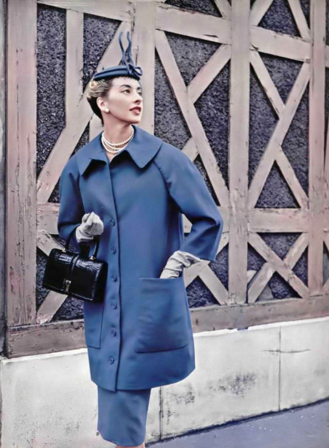 Marie-Thérèse in 7/8 coat cut full in the back worn over slim jersey dress in same color by Jacques Fath, croc handbag by Amaryllis, 1954