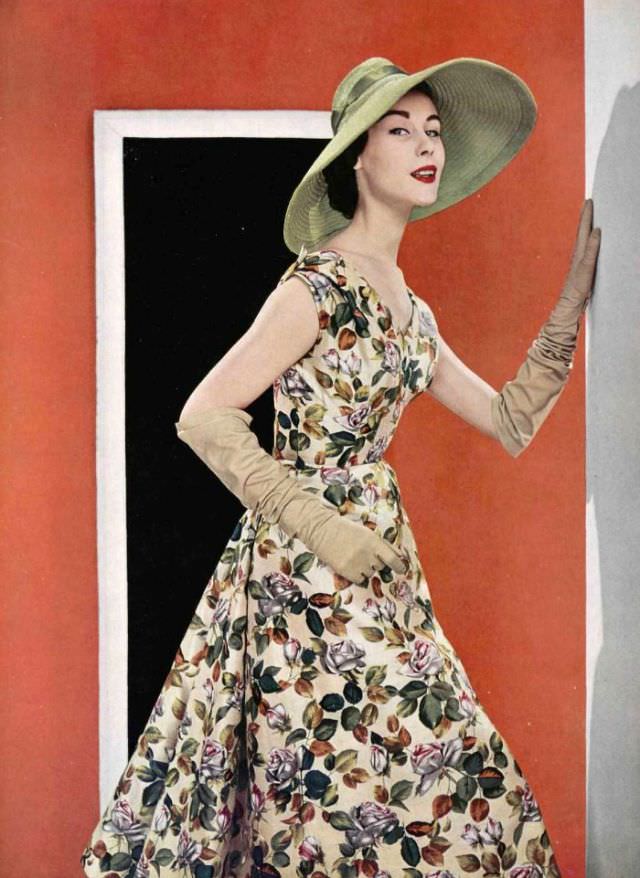 Myrtle Crawford in a silk floral print afternoon dress worn with wide-brimmed green straw hat, by Jacques Fath, 1954