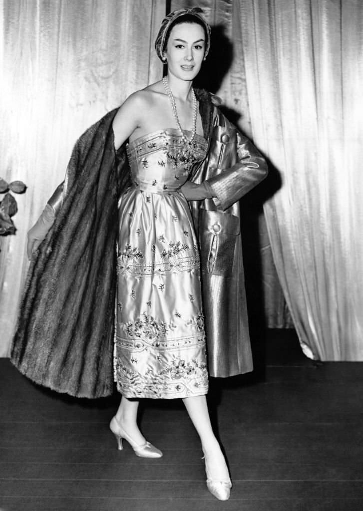 Model showing a cocktail dress, in beige satin with her coat from the autumn 54 collection. Model Jacques Fath at the Dorchester Hotel, London on September 29, 1954.