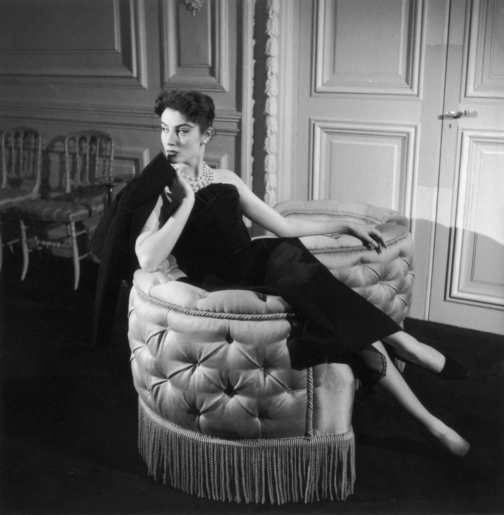 Genevieve Fath lounges in a loveseat, wearing an outfit designed by her late husband, Jacques Fath, 1955