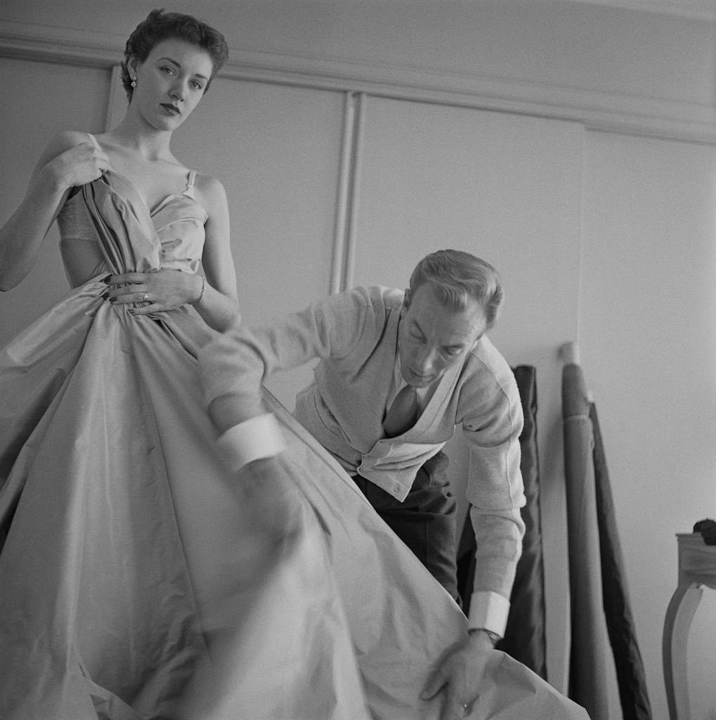 Famous haute couture designer, Jacques Fath arranges a model's dress