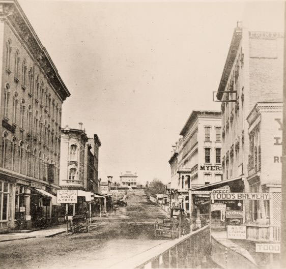 View from along right side of bridge of Milwaukee Street looking east in Janesville, 1870