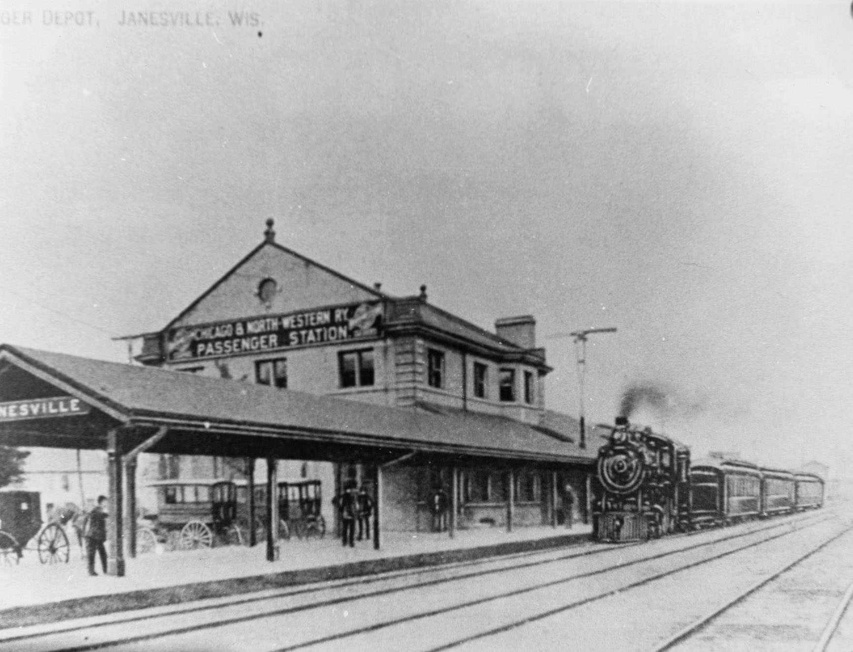 The Chicago and North Western Railroad depot in Janesville with a steam locomotive on the track, 1890