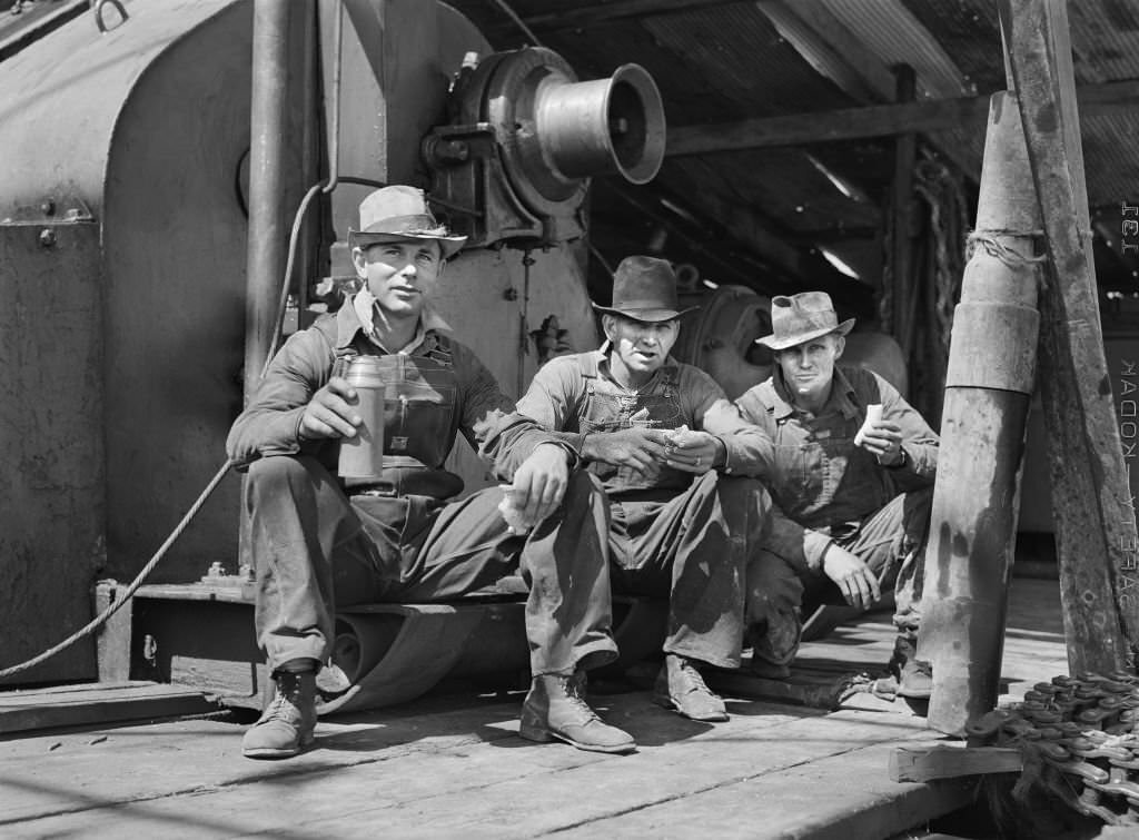 C.L. Saxton, Driller, J.G. Betz, Cathead Man and L.C. Westerman, eating Lunch around Oil Well, Continental Oil Company, Moundridge, Kansas, September 1941