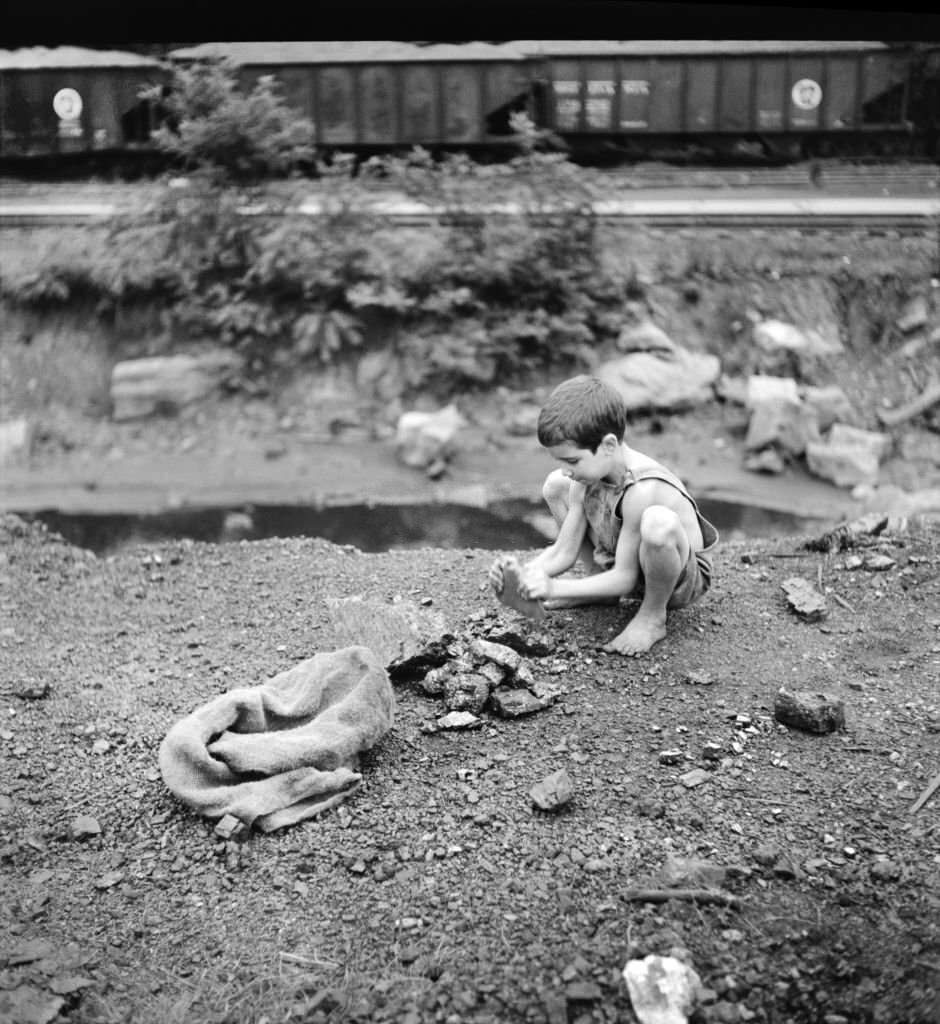 Coal Miner's Child breaking up large pieces of Coal to take home, Scotts Run, West Virginia, 1939