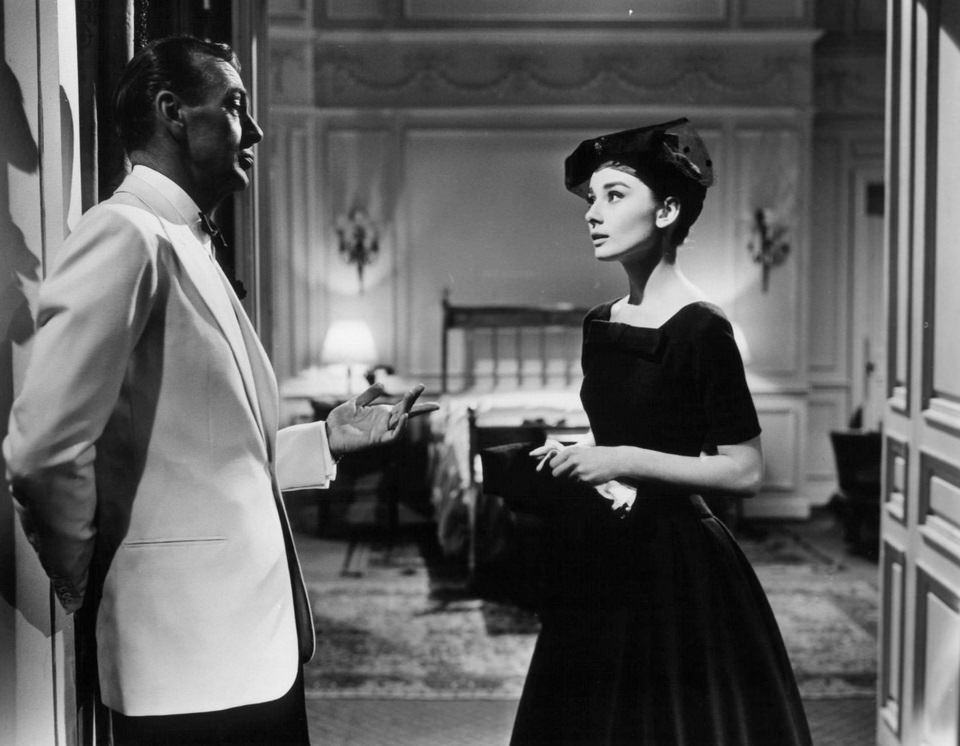 Gary Cooper leaning against wall as he talks with Audrey Hepburn in a scene from the film 'Love In The Afternoon', 1957.