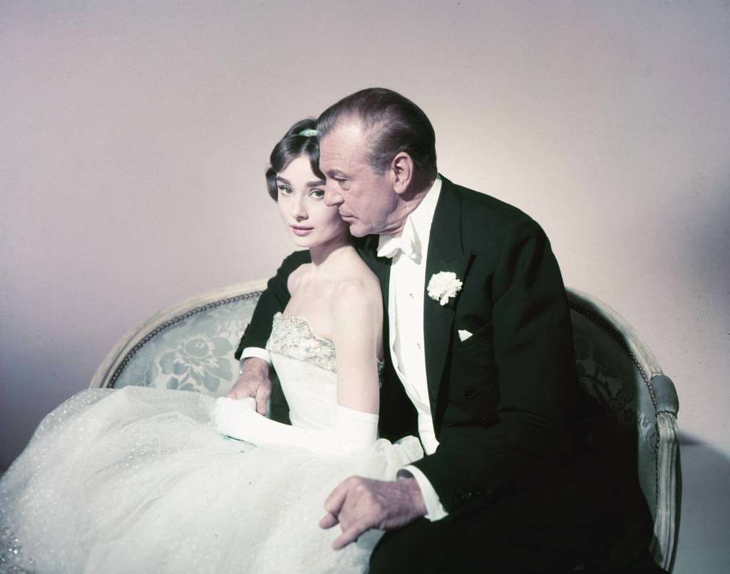 Audrey Hepburn wearing a strapless white dress, and Gary Cooper , wearing a black dinner jacket, white shirt with wing-top collars and a white bow tie, 'Love in the Afternoon', 1957.