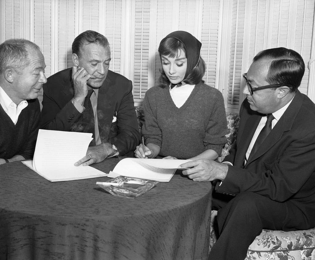 Producer and director Billy Wilder, Gary Cooper, Audrey Hepburn and Harold J. Mirusch, Allied Artists vice president, signing the contracts for the production of 'Love in the Afternoon'.