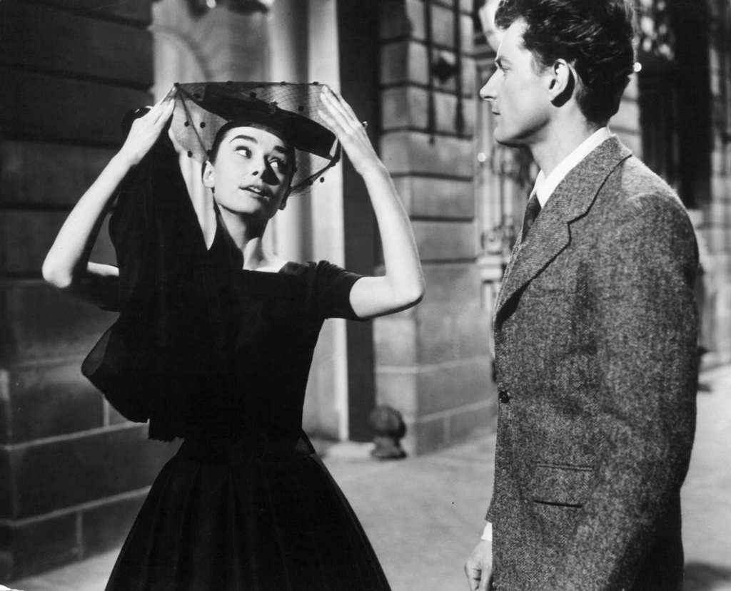 Audrey Hepburn pulling her veil away as she speaks to a man in a scene from the film 'Love In The Afternoon', 1957.