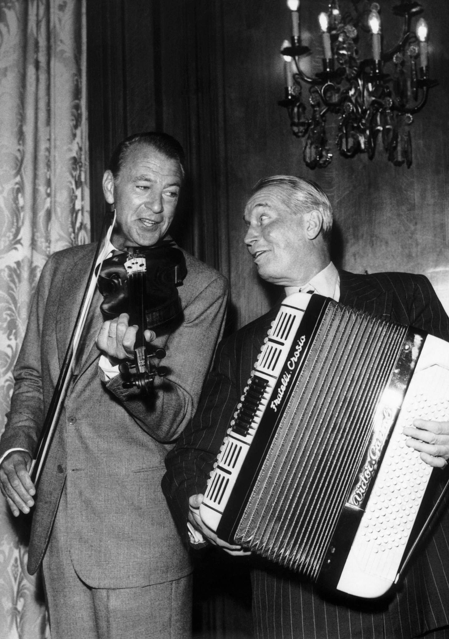 Maurice Chevalier and Gary Cooper, the two actors are playing music during the party held for the release of the movie 'Love in the Afternoon' on June 18, 1957 in Paris, France.