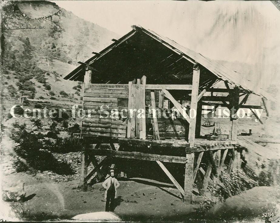 View of man, possibly James Marshall, standing in front of Sutter's Mill sometime after the discovery of gold, 1850