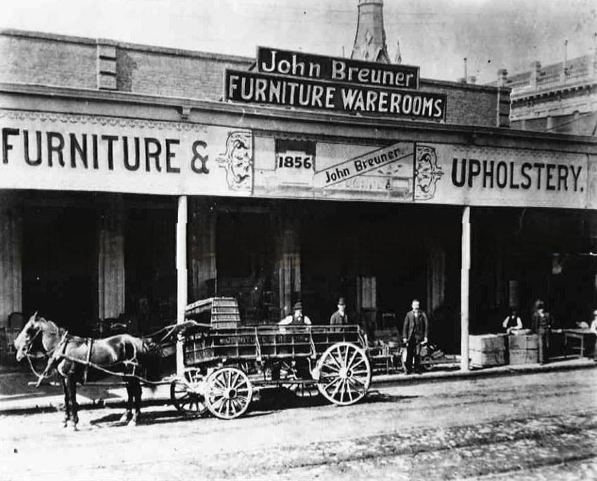 Exterior view of John Breuner Furniture Warerooms showing the delivery wagon and six men posing next to the wagon in front of the store, 1856