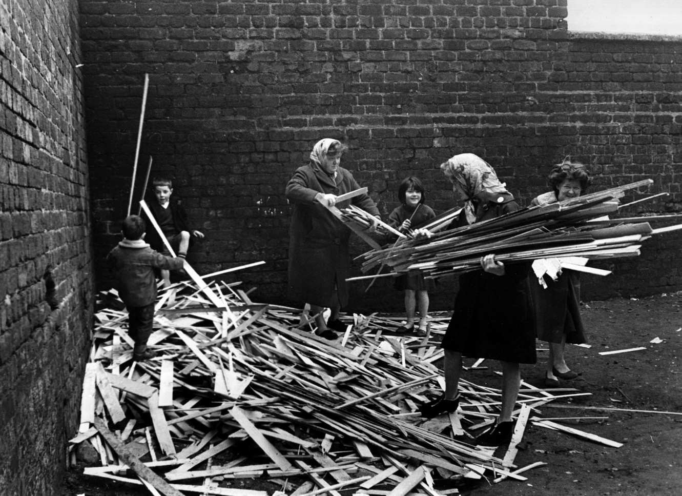 Residents of the Gorbals area of Glasgow collecting firewood among partially-demolished tenement buildings, 1960