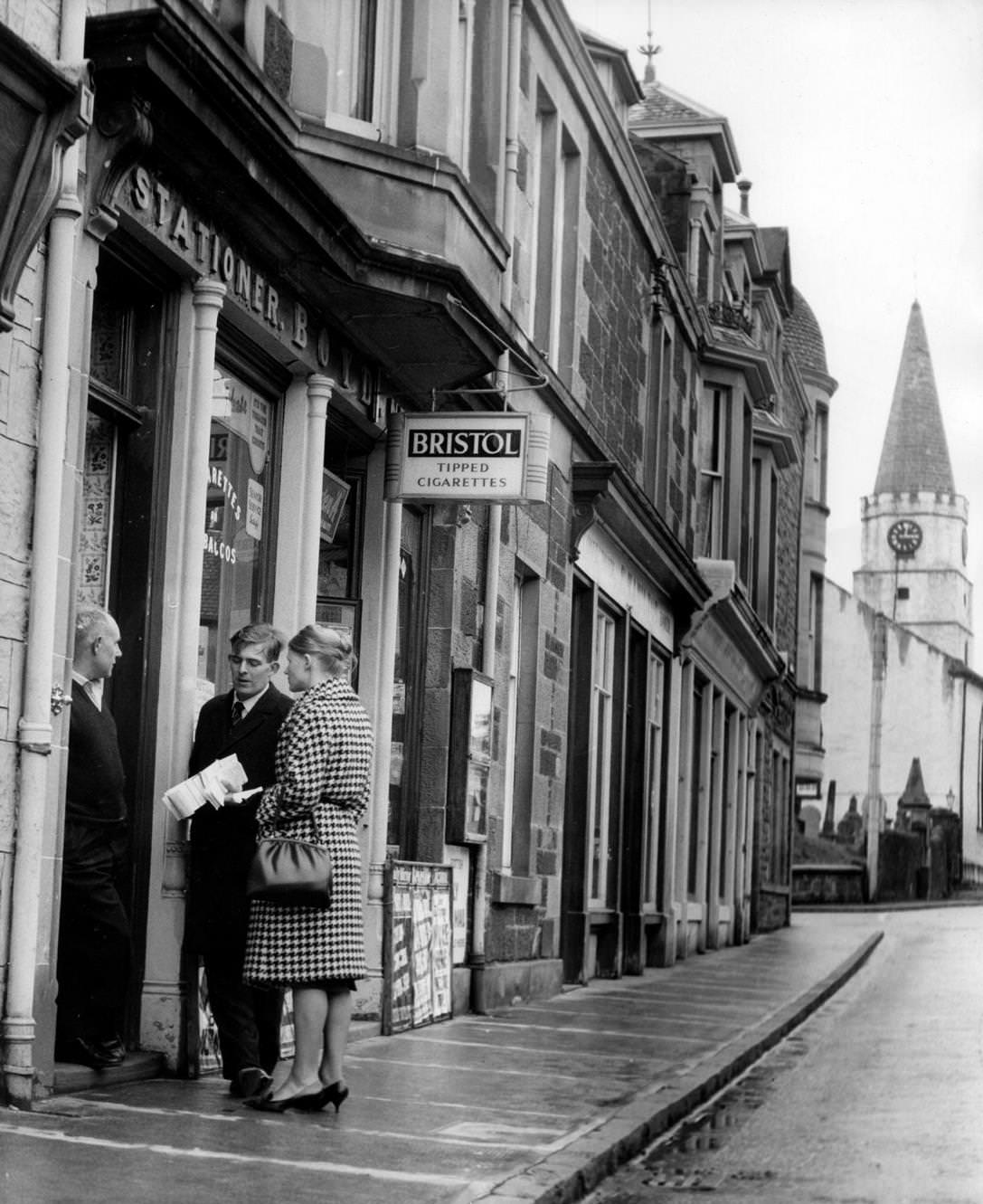 Candidate Andrew Forrester and his wife chat with a shopkeeper in Comrie, Scotland, 1963