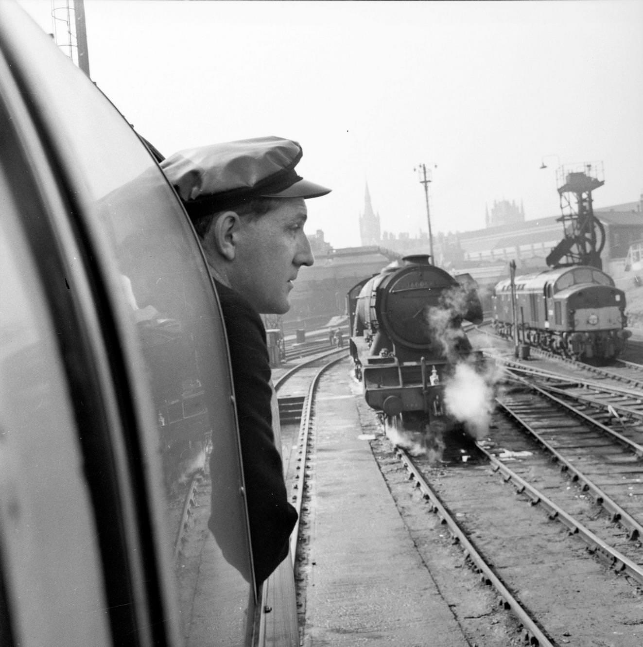 The railway employee responsible for the oiling on board the Flying Scotsman looks at an old steam locomotive in a siding at King's Cross Station in London as the train leaves for Edinburgh on its centenary journey, 1962