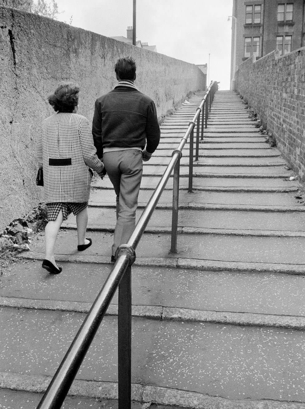 A couple make their way up a flight of steps in Greenock on the Clyde, Scotland, 1963