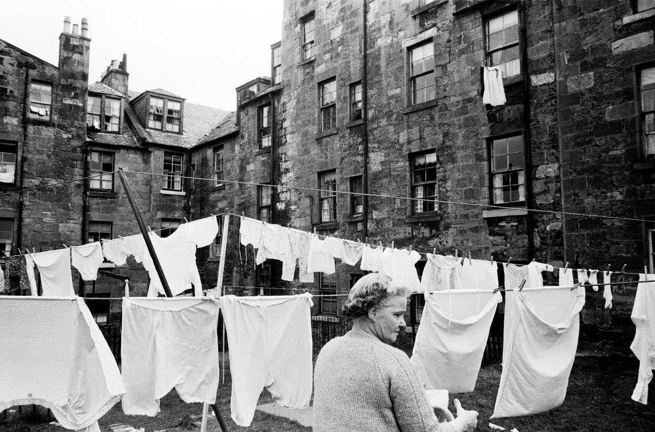 A woman hangs out her laundry on a washing line between tenements in Greenock, Renfrewshire, Scotland, 1963.