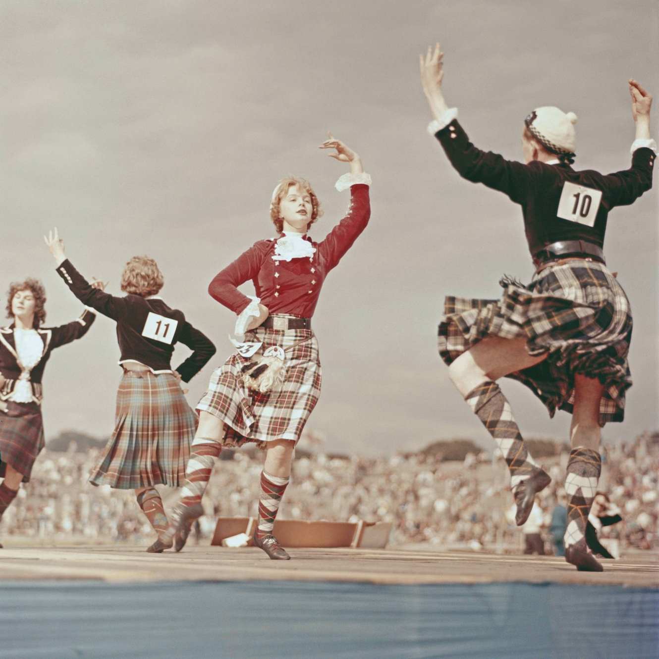 Young female dancers competing in a Highland Dancing contest on a wooden stage at a sports stadium in Edinburgh, Scotland in 1960.