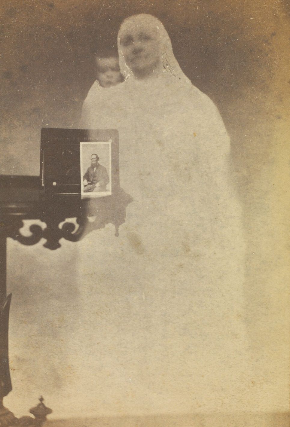 A portrait of Mr. Tinkham perched on a side table, with the faint image of a woman and baby next to it.