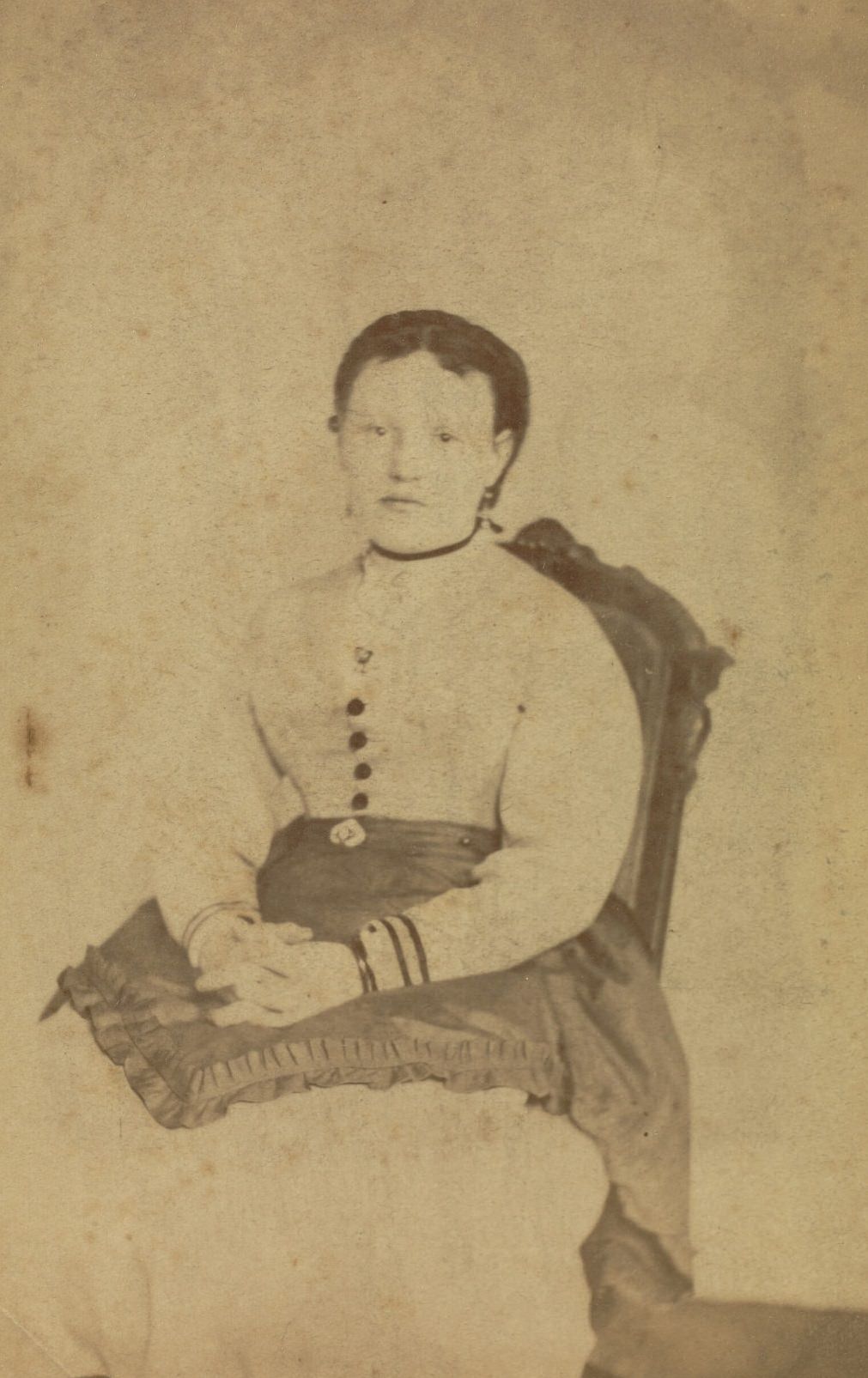 Portrait of a woman seated with her hands clasped in her lap.