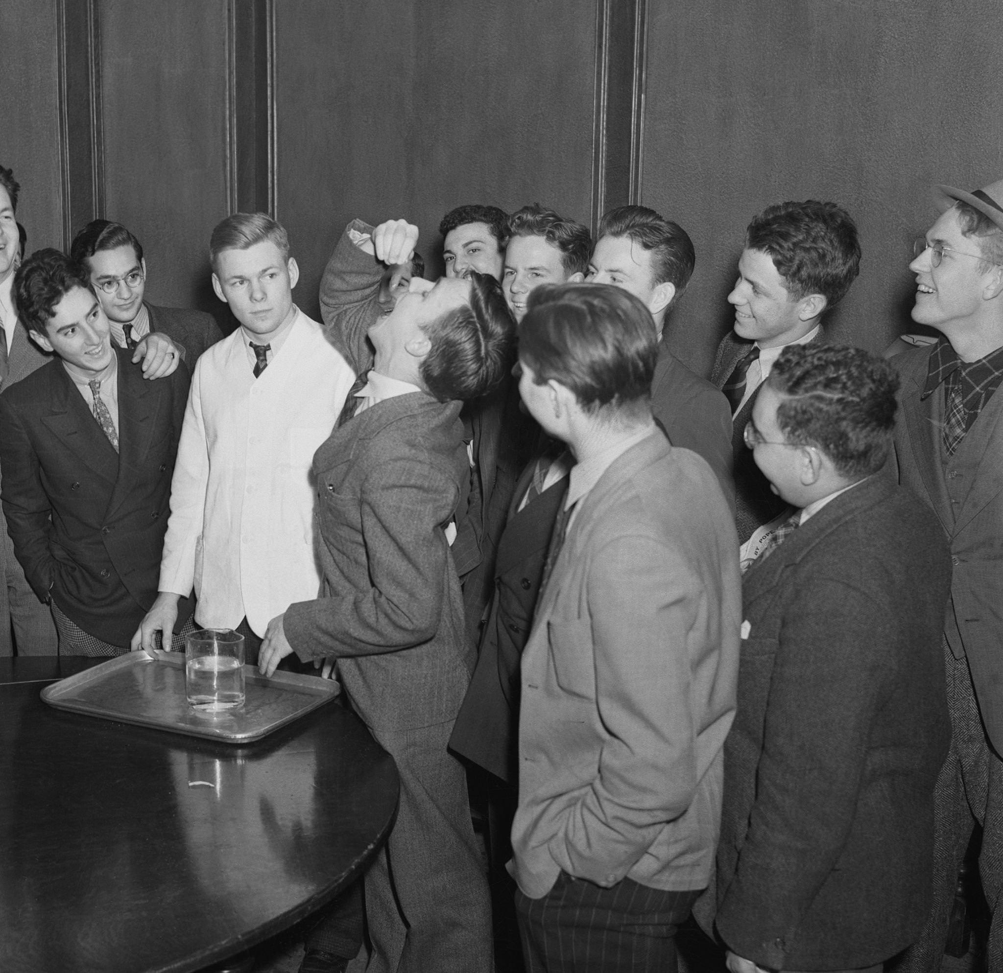 Harvard Student Swallows Goldfish while laughing class mates look on.