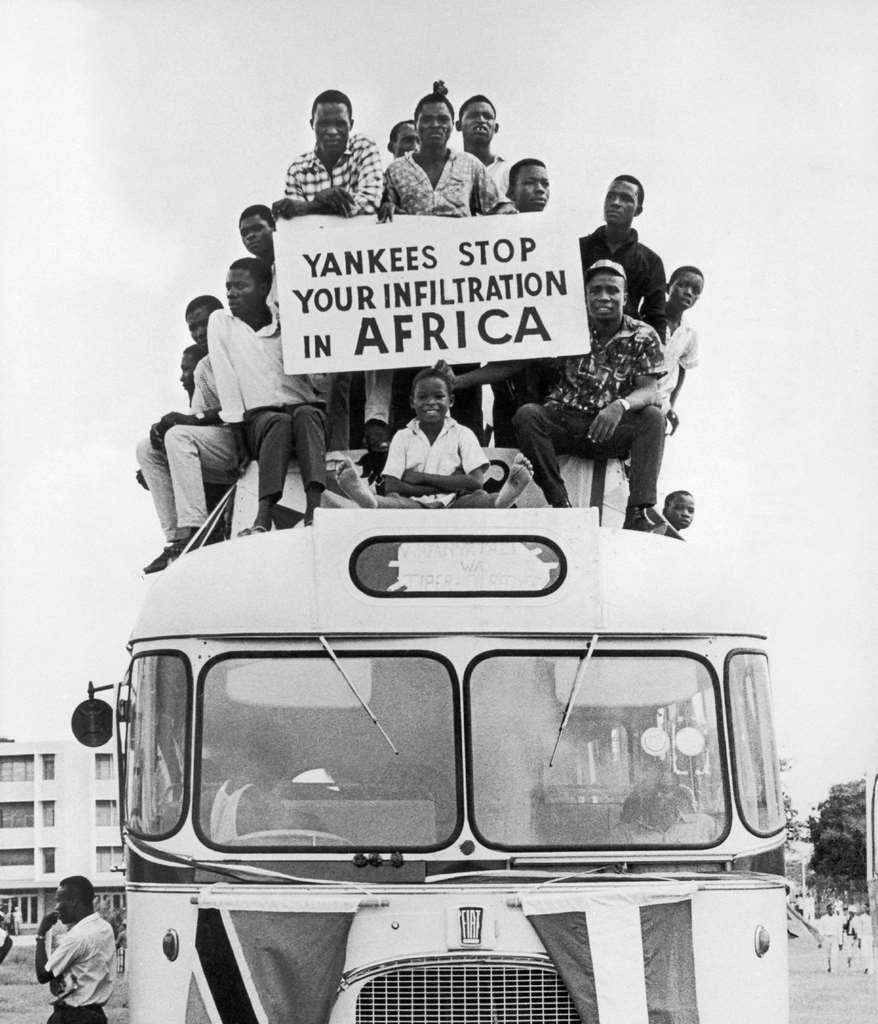 On the roof of a bus, Tanzanians protest against US imperialism with a banner that reads 'Yankees, stop infiltrating Africa', in Tanzania, August 4, 1967.