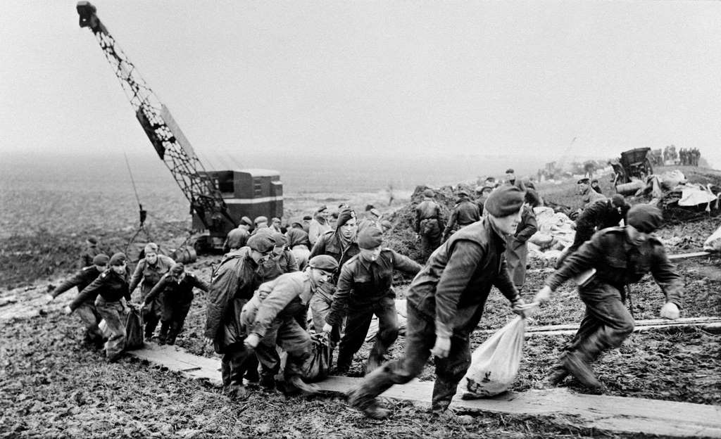 Soldiers and civilians are seen on a beach gathering sandbags to strenghthen against the spring tide in Netherlands, 1953