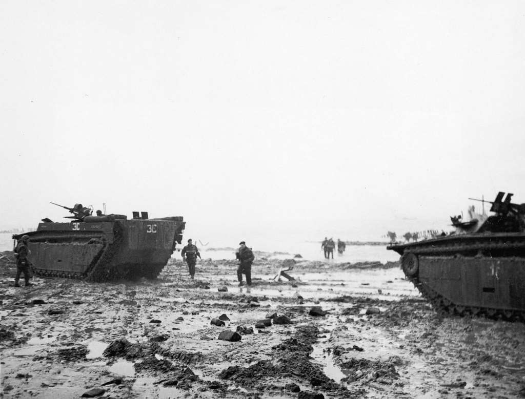 Amphibious tanks on the beach, showing troops wading ashore in the background, 1950s