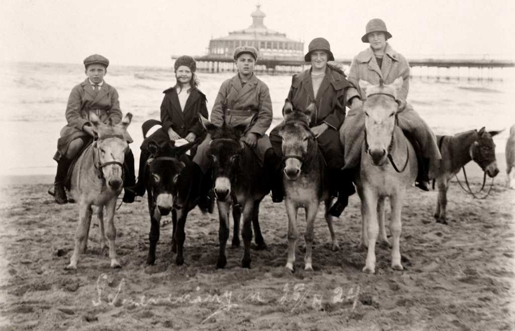 Donkey rides at the seaside, with the pier behind, in Scheveningen near The Hague in the Netherlands, 1924.