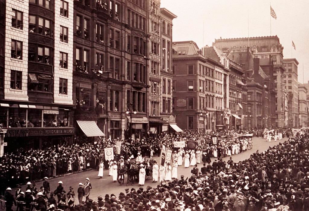 View of a suffrage parade on a city street flanked by a large crowd, 1913