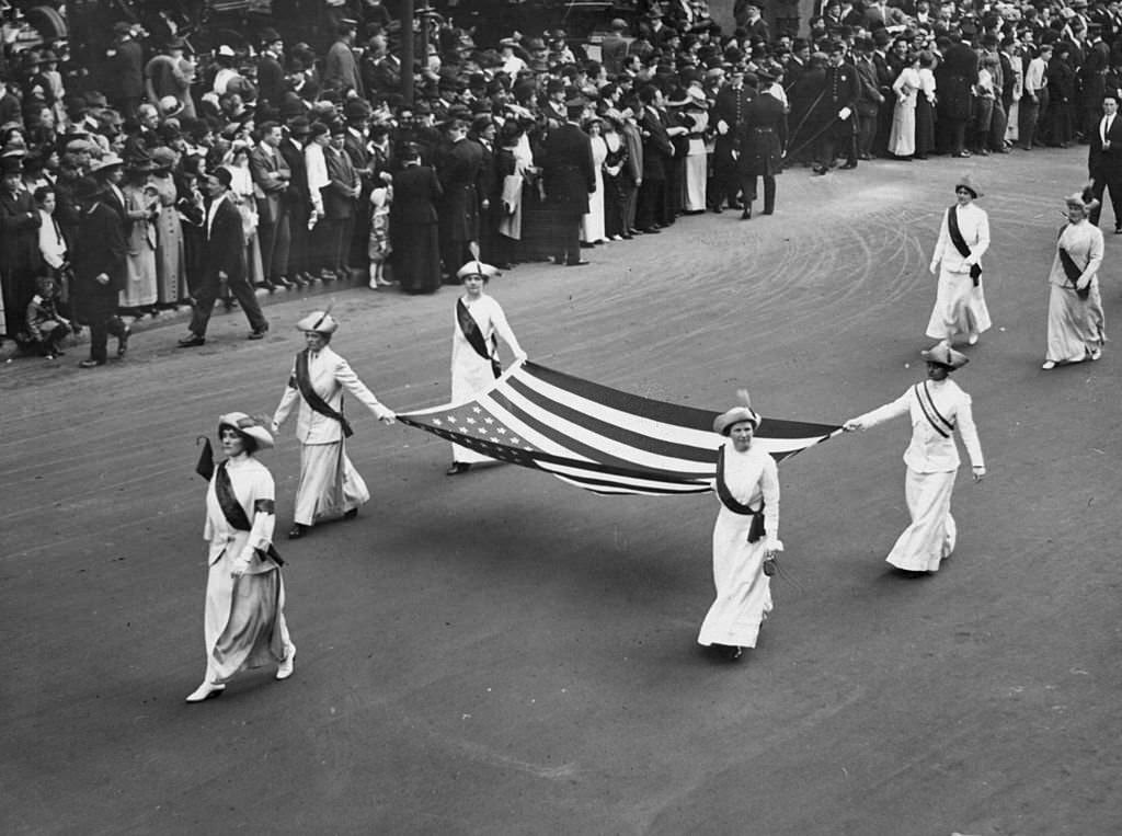 A group of ladies carrying the American flag on a Women's Suffrage Parade, 1913