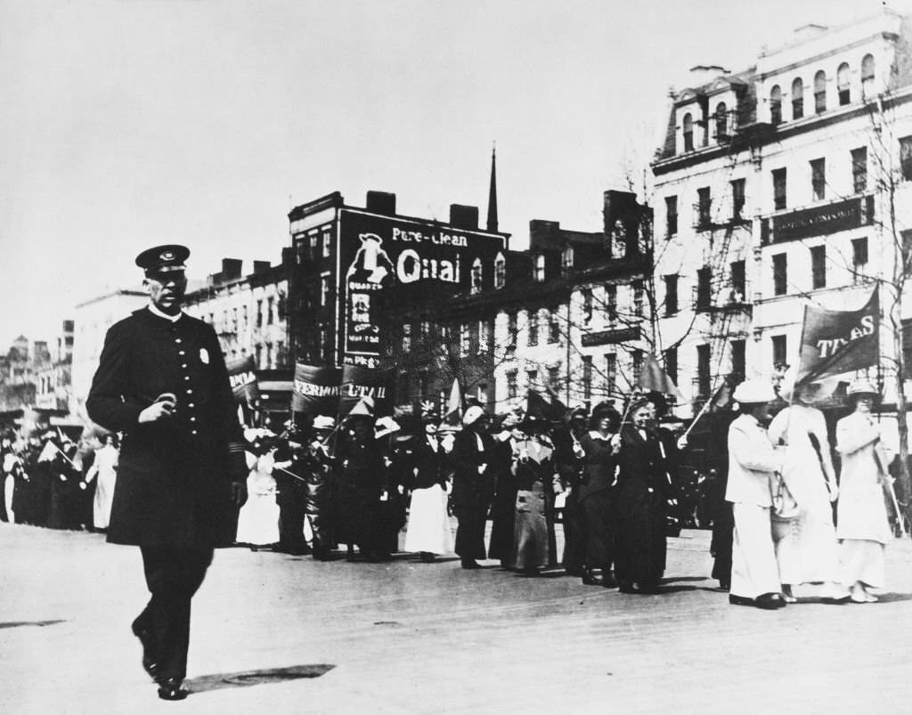 A police officer supervising a group of suffragettes during a parade in Washington DC, US, 7th April 1913.