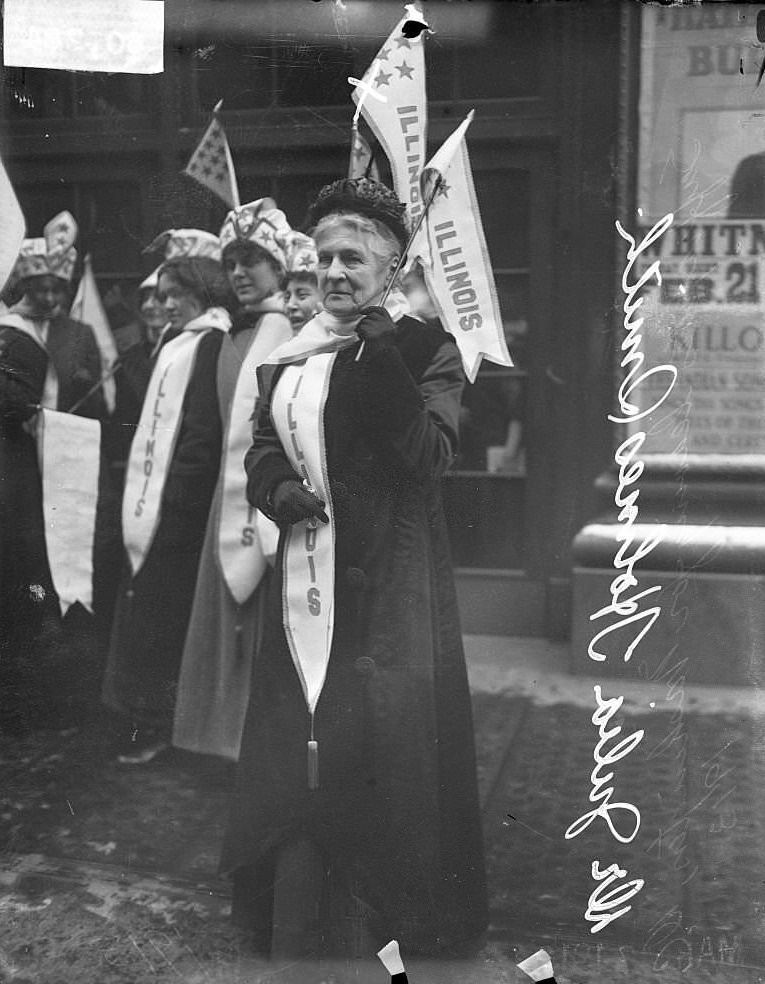 Suffragette Dr Julia Holmes Smith, wearing a banner and holding a flag, demonstrating with other suffragists in Chicago, Illinois, February 27, 1913.