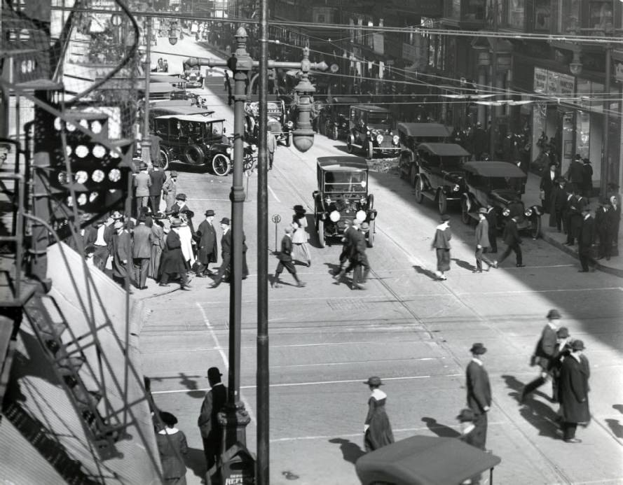 Olive and 7th Street, looking east. Hanover and Regal shoes in the right foreground. Many pedestrians crossing the street, 1909