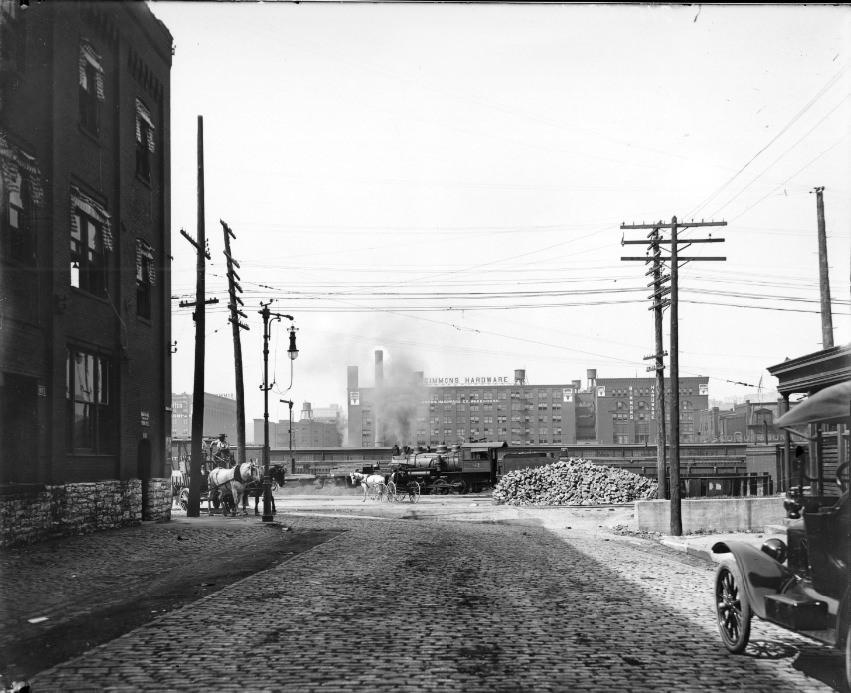 A cobblestone cross-street fitted with a gas powered street light and a series of telephone wires, 1908