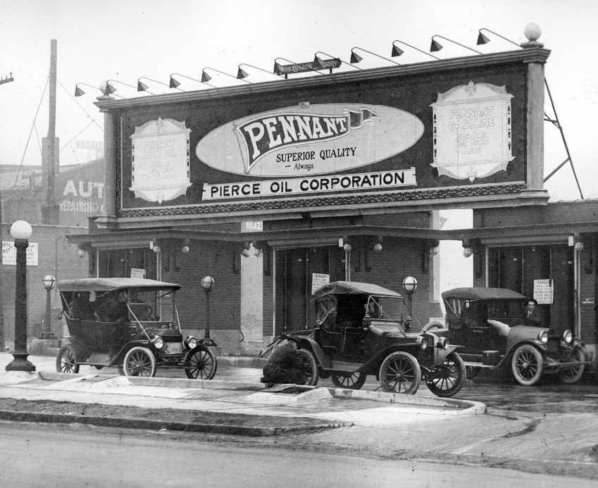 A Pennant Pierce Oil Corporation filling station, 1908. Three cars are visible in front. A man appears to be putting air into the tire of one of the cars.