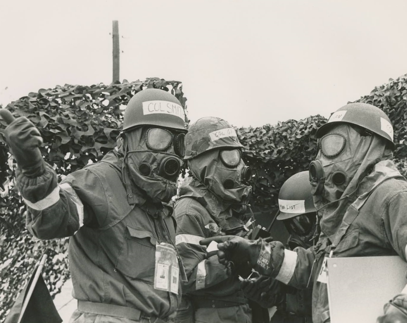 Several officers in gas masks standing together during a mock casualties and chemical warfare exercise at the Bergstrom Air Force Base, 1973