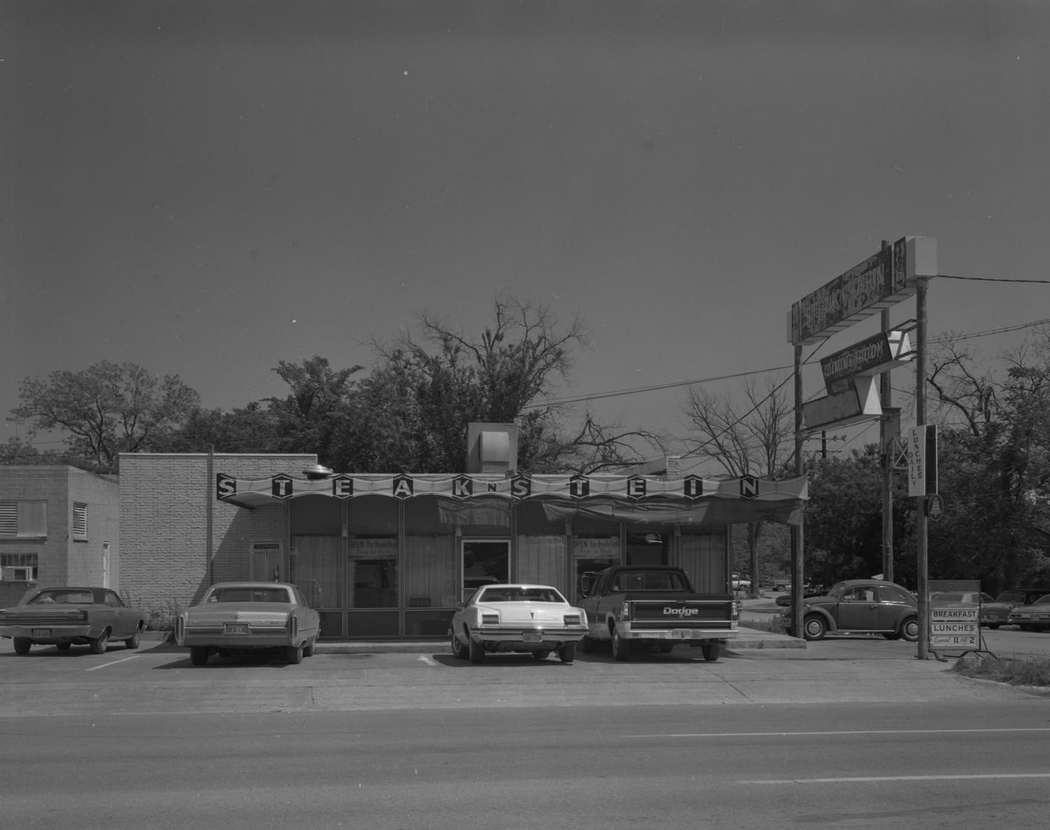 A small diner called Steak 'N' Stein with an old neon sign that can be seen on a tall stand to the right, 1973