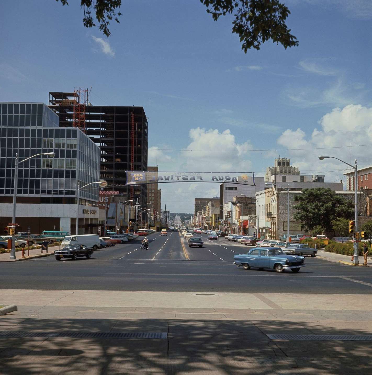 Cars drive up and down Congress Avenue at the intersection with 11th Street in the downtown district of the city of Austin, 1970