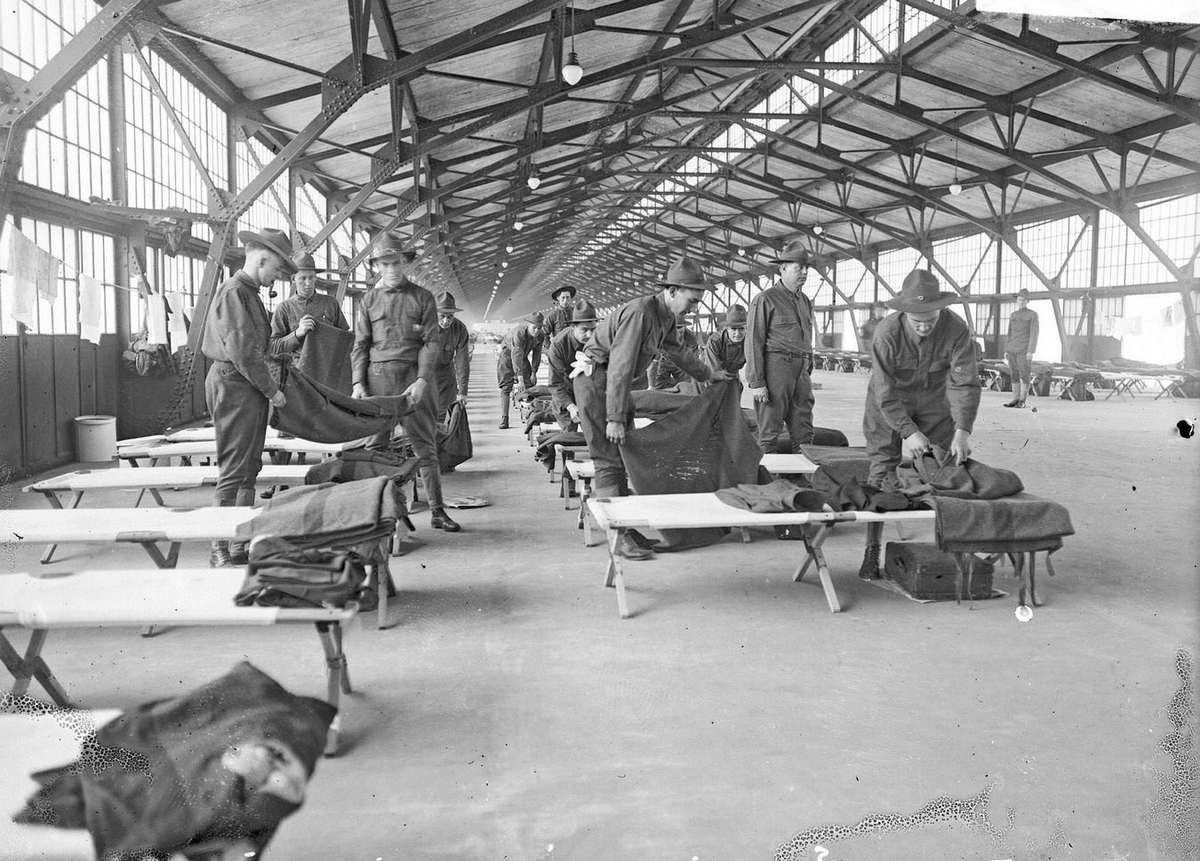 US Army 3rd Reserve Engineers folding blankets at their cots set up in the building at the Municipal Pier (Navy Pier), Chicago, Illinois, 1910s.