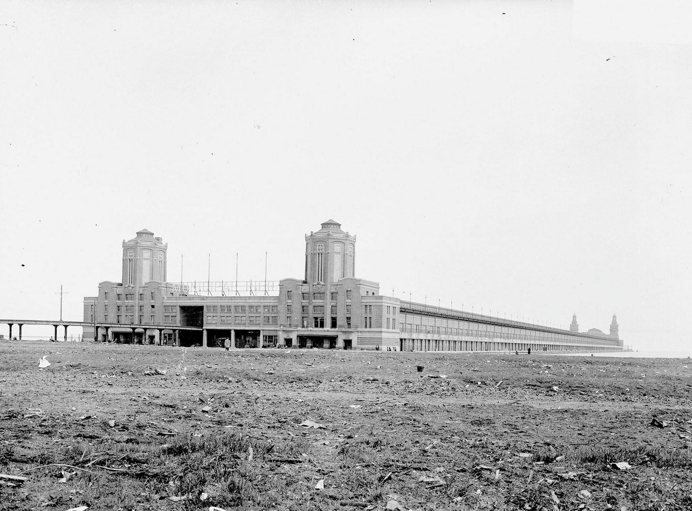 Municipal Pier (now called Navy Pier) under construction, seen from across a dirt field in front of it, in the Near North Side community area, Chicago, Illinois, 1910s.