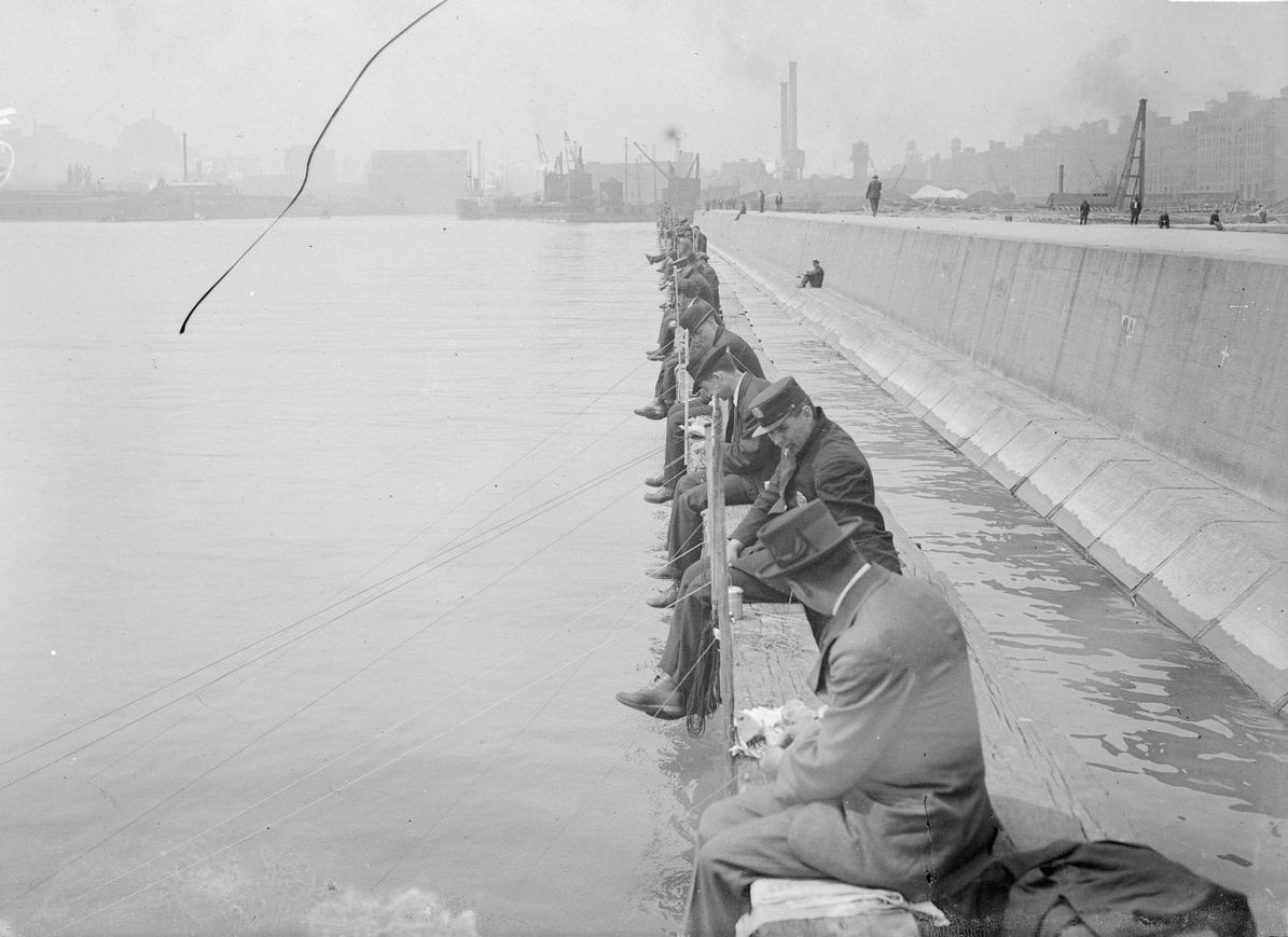 Men fishing from North Pier, sitting along a breakwater at the mouth of the Chicago River, Chicago, Illinois, 1910s.