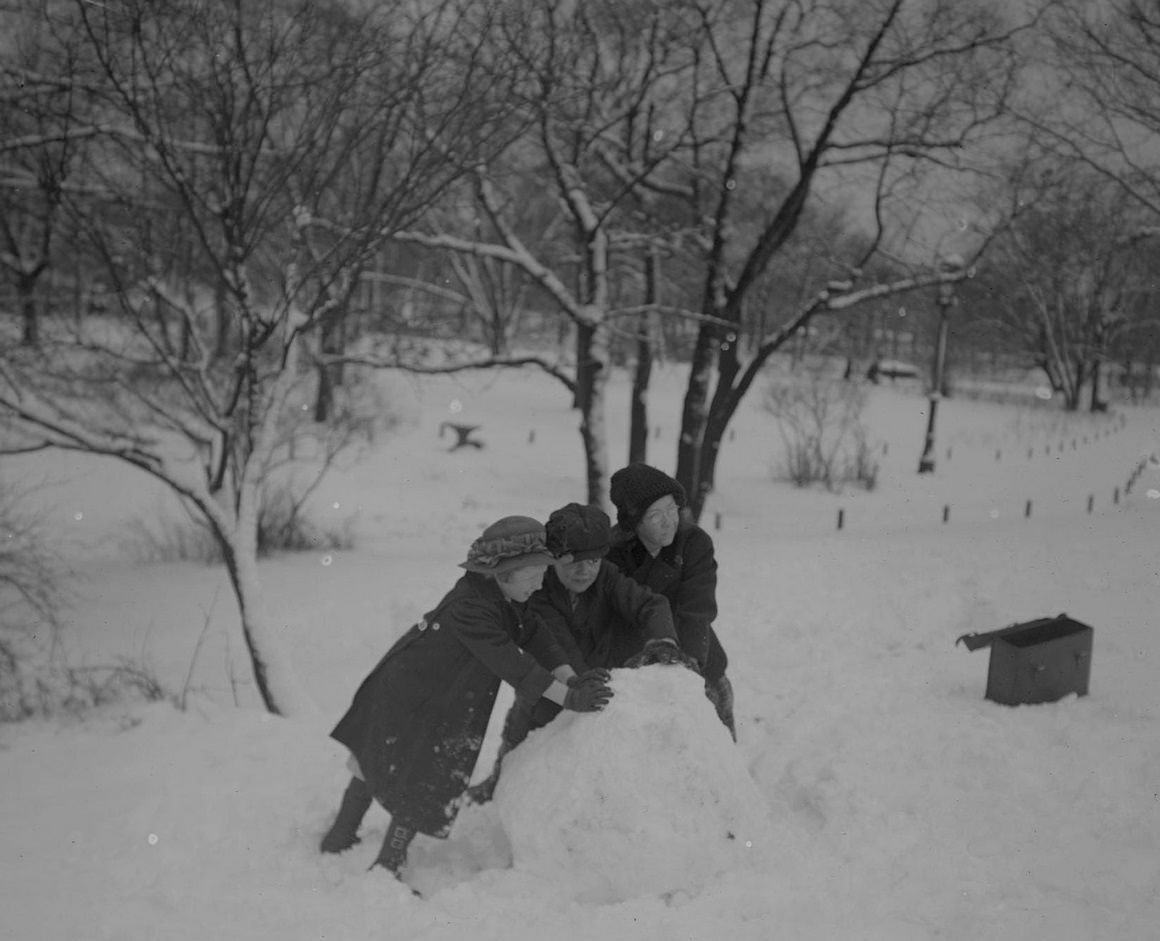 Children rolling up a large ball of snow in Lincoln Park, Chicago, Illinois, 1910s.